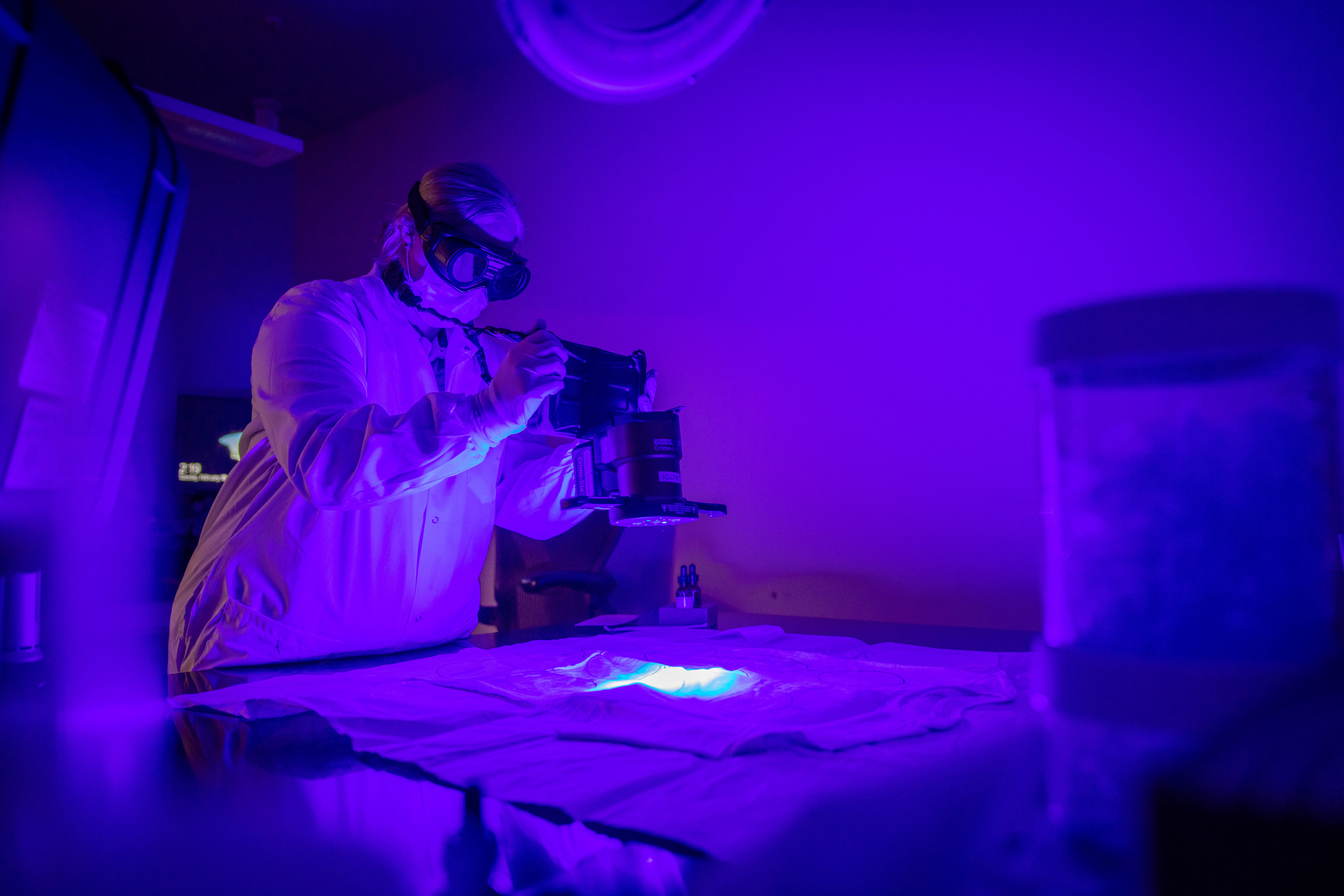 Scientist uses an alternate light source to look for serological material