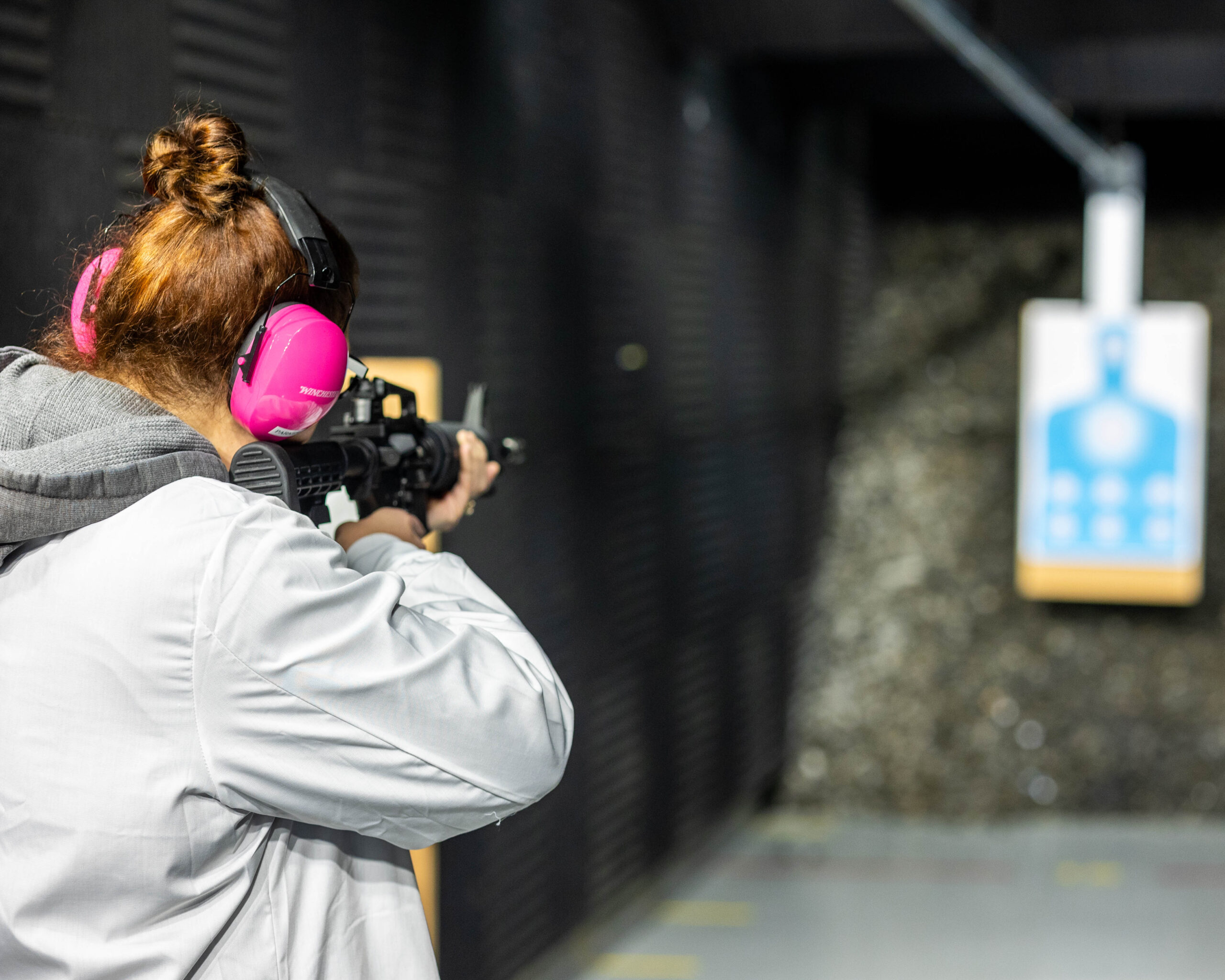 A forensic scientist fires a weapon in the indoor range