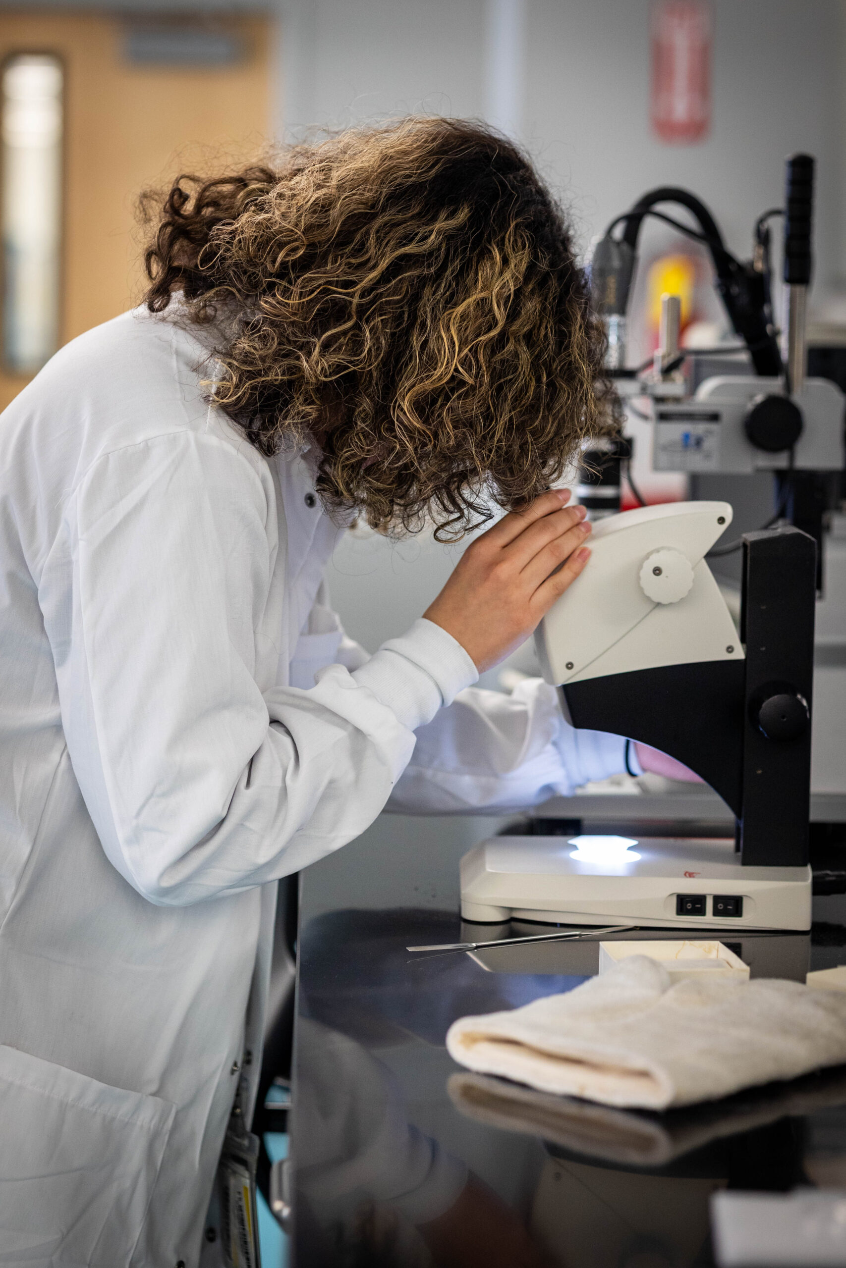 A woman is shown looking into a microscope