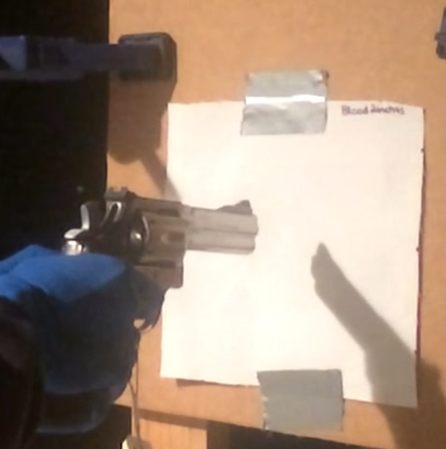 A gun is held in front of a paper in preparation for a distance determination